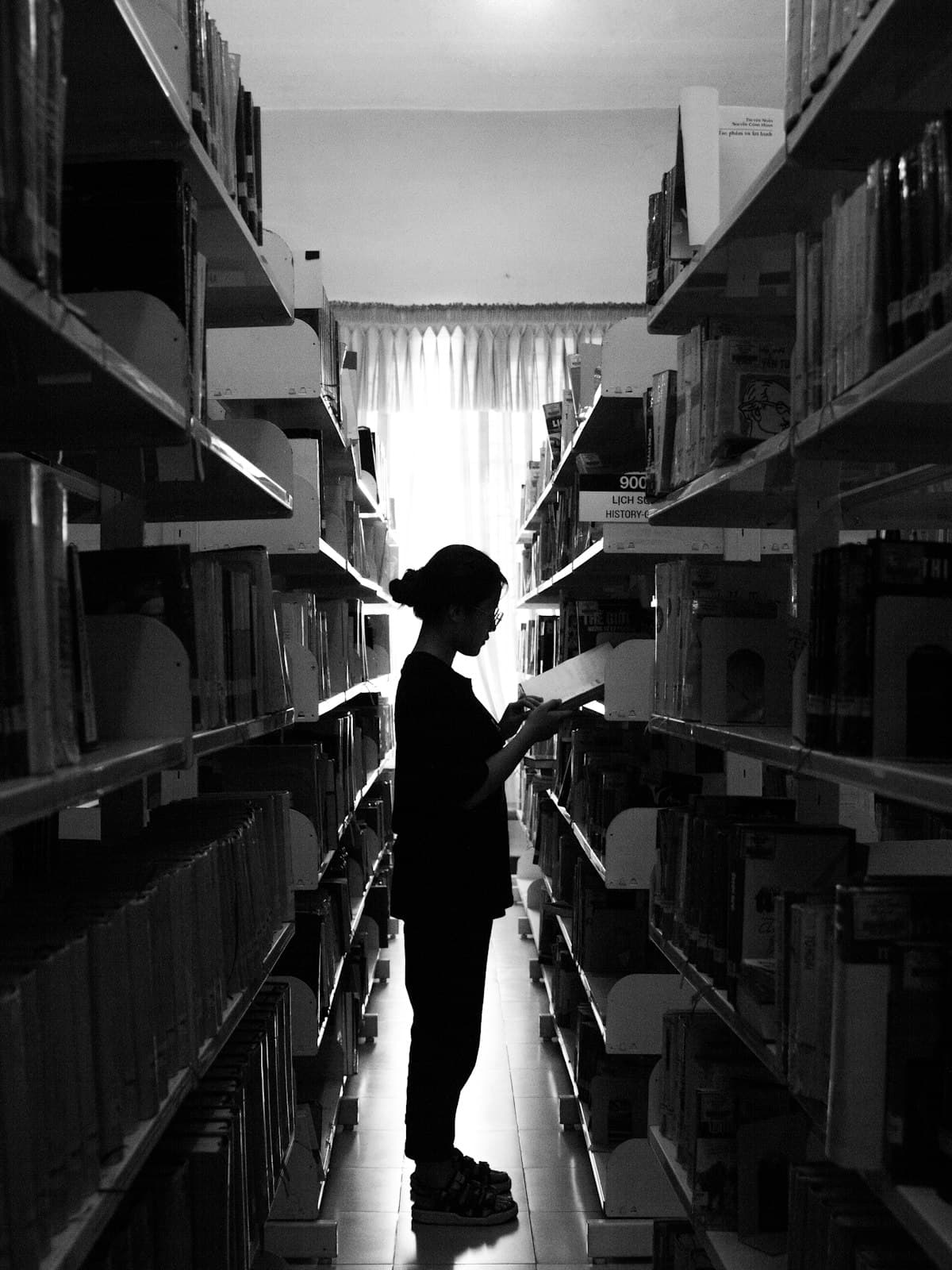 A person silhouetted between library stacks